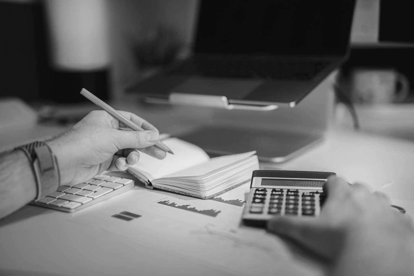 Working through figures with a pencil, calculator, notebook and printed financial report